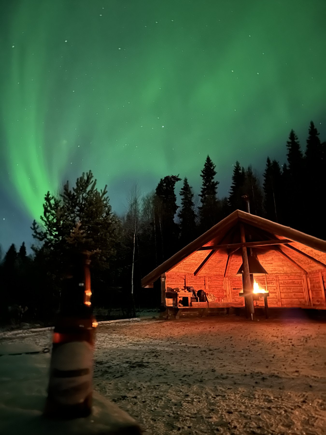 Aurora above a firelit cabin in Finland